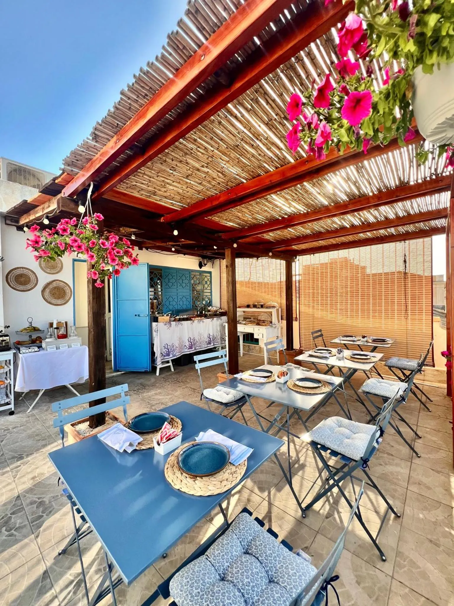 Terrasse ombragée avec tables et chaises pour les repas.