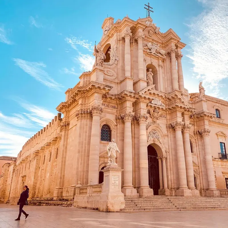 Façade d'une église baroque en pierre claire sous un ciel bleu.