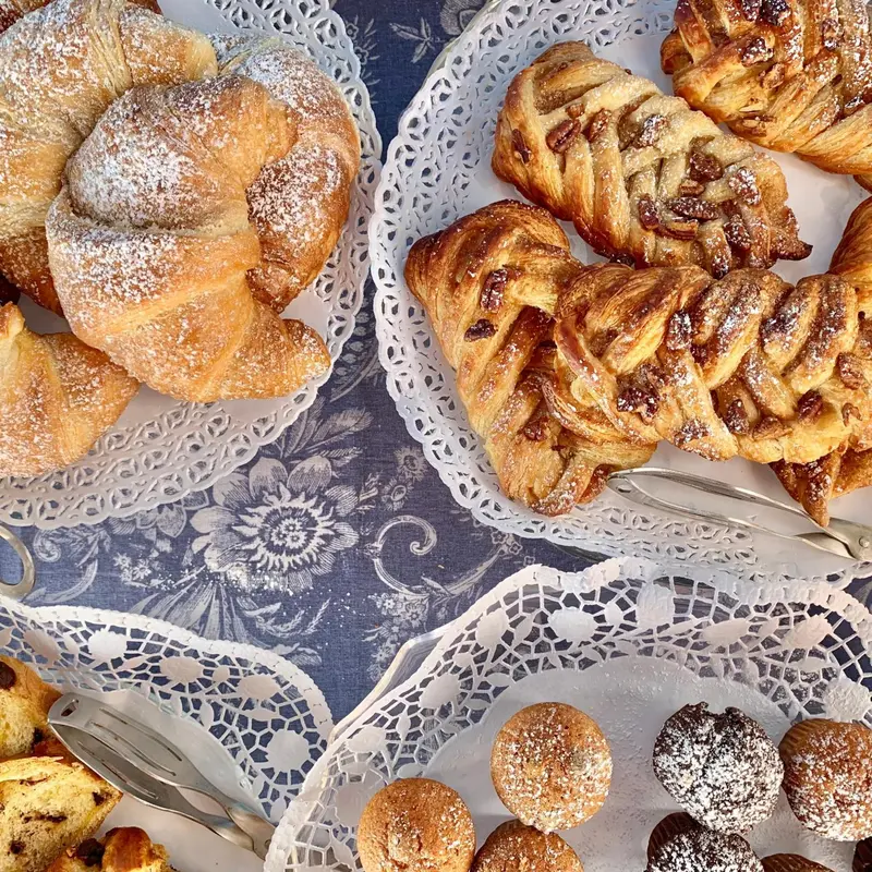 Assortiment de viennoiseries et de pâtisseries sur des plateaux décorés.