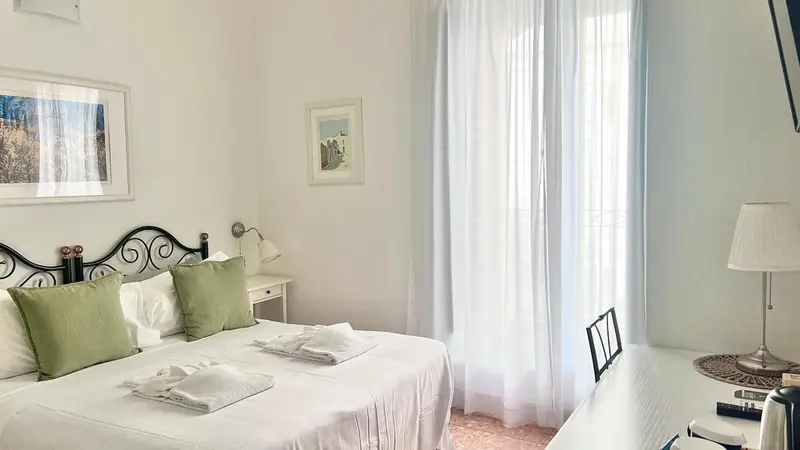 Une chambre lumineuse avec un lit recouvert d'oreillers verts et de couvertures blanches.