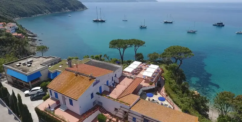 Vue aérienne d'un complexe hôtelier surplombant une crique turquoise.
