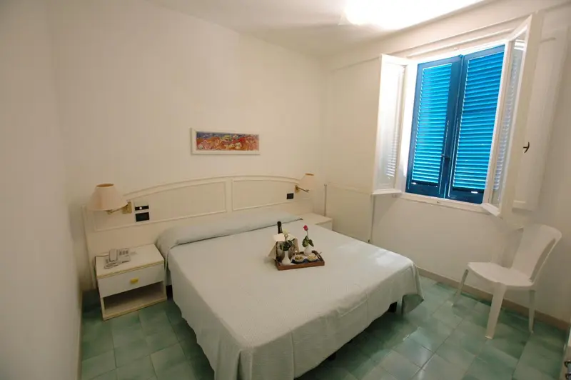 Une chambre lumineuse avec un lit et une fenêtre à volets bleus.