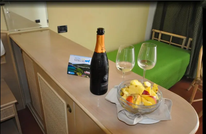 Une table basse présente une bouteille de champagne, deux verres et une salade de fruits.
