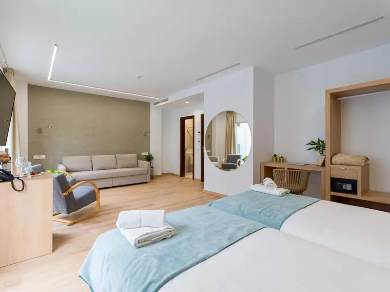 Une chambre lumineuse avec un canapé et un lit fait.