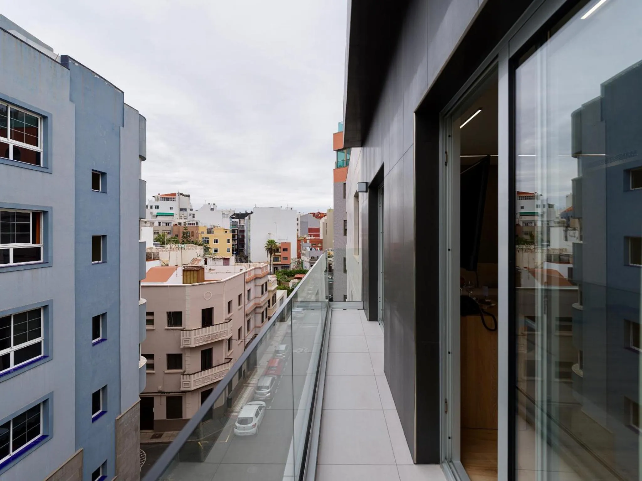 Vue d'un balcon moderne avec garde-corps en verre donnant sur une ville côtière.