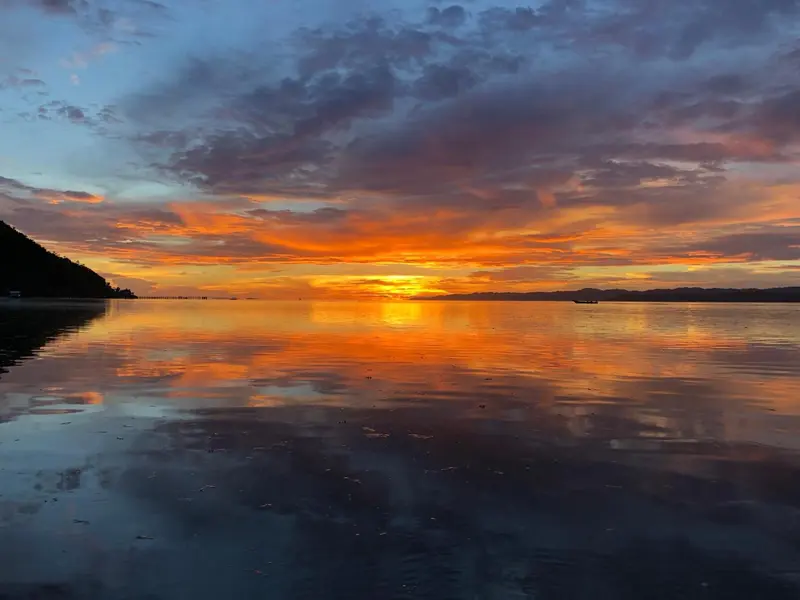 Ciel flamboyant au coucher du soleil sur une mer calme.