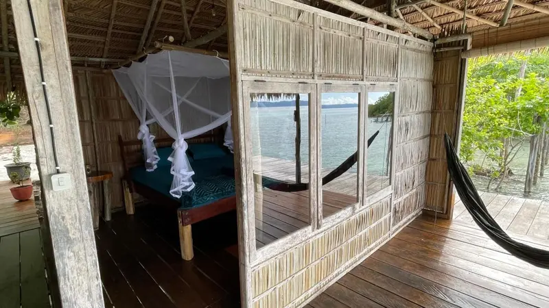 Une chambre rustique avec un lit à baldaquin donnant sur la mer.