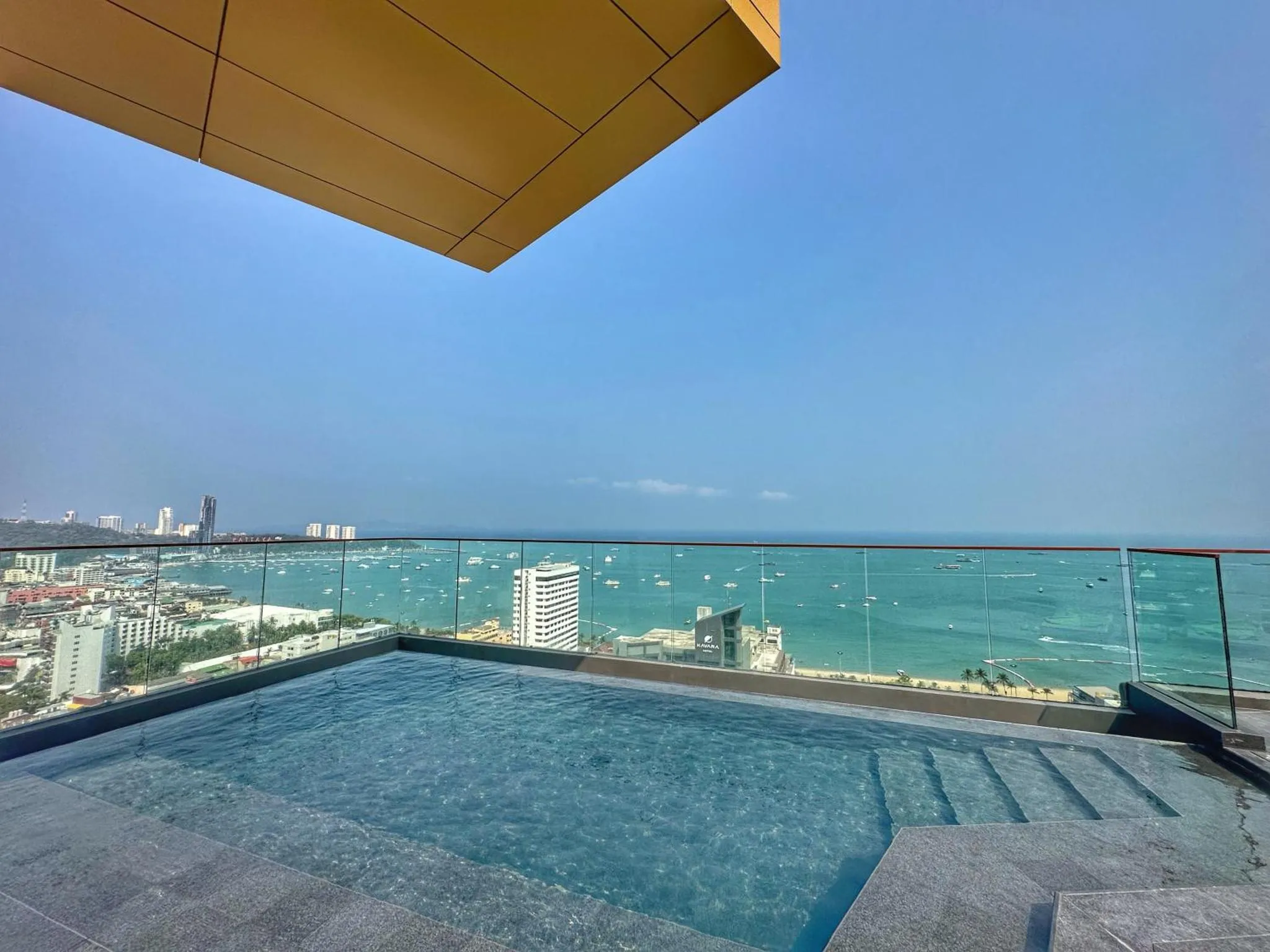 Une piscine sur une terrasse avec vue sur la mer et la ville.