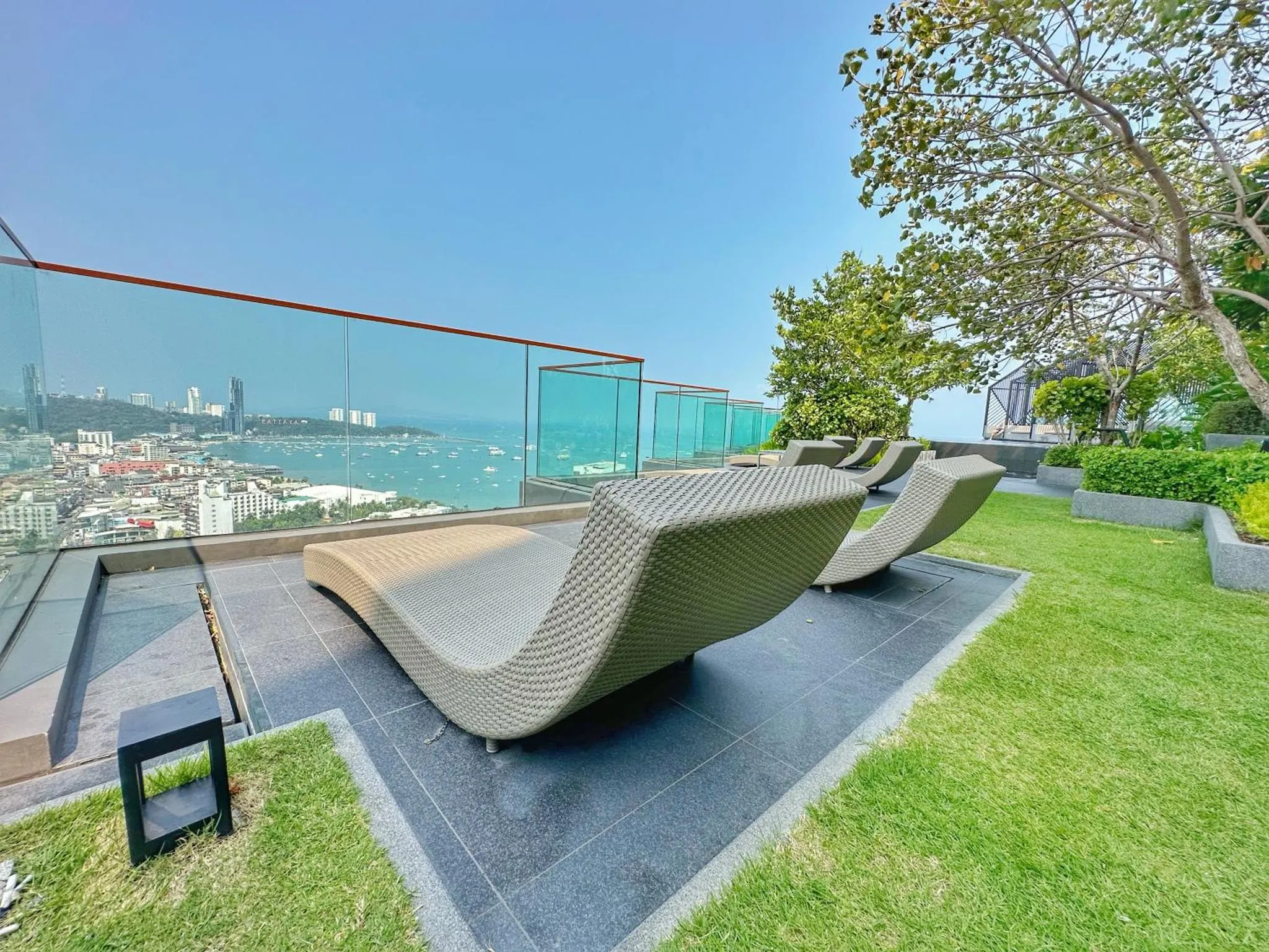 Transats sur une terrasse avec vue sur la mer et la ville.