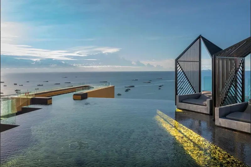 Piscine à débordement avec vue sur la mer et des bateaux à l'horizon.