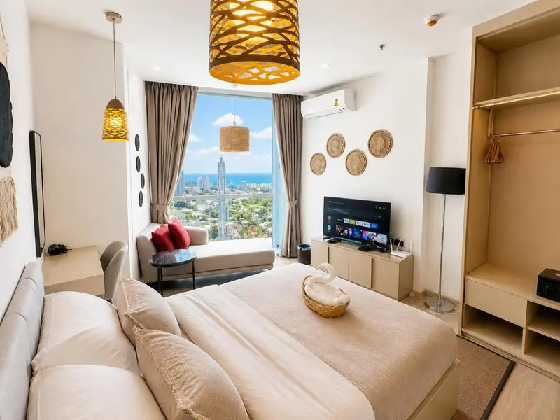 Une chambre lumineuse avec un grand lit et une vue sur la ville.