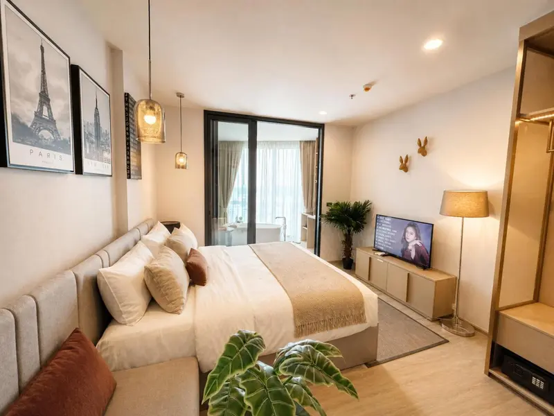 Chambre lumineuse avec un grand lit et une décoration sobre.