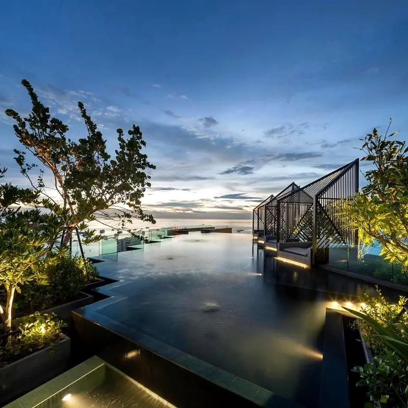 Piscine à débordement avec vue sur la mer au coucher du soleil.
