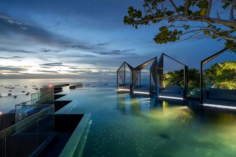 Piscine à débordement avec vue sur la mer au coucher du soleil.