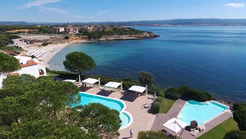 Vue aérienne d'une piscine d'hôtel surplombant une plage et la mer.