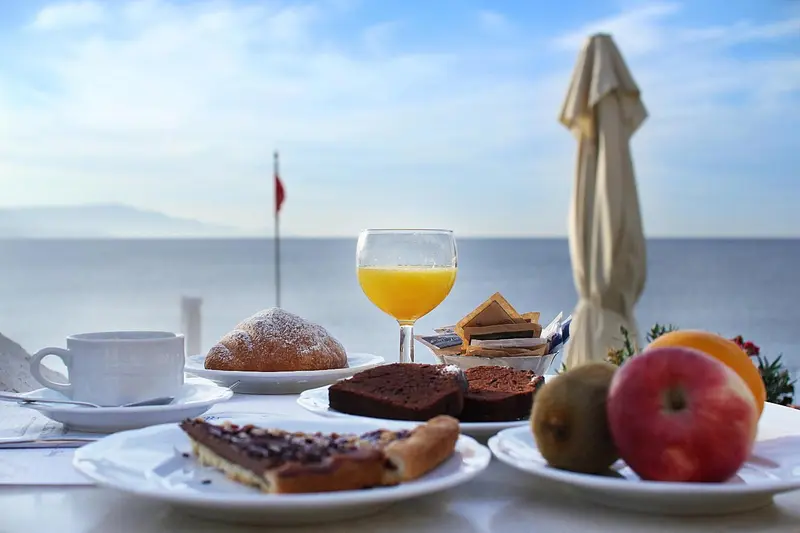 Un petit-déjeuner est servi sur une table en terrasse avec vue sur la mer.
