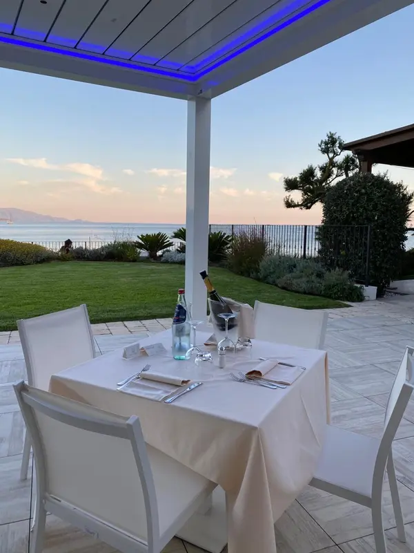 Table dressée en extérieur avec vue sur la mer au coucher du soleil.