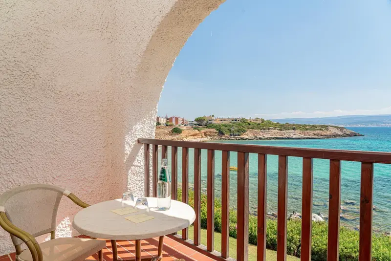 Une petite table ronde avec deux chaises sur un balcon donnant sur la mer.