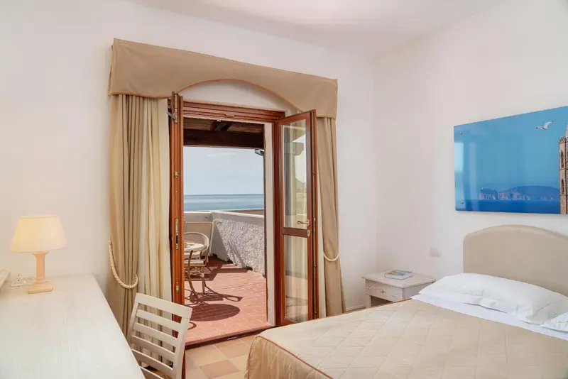 Une chambre lumineuse s'ouvre sur une terrasse avec vue sur la mer.