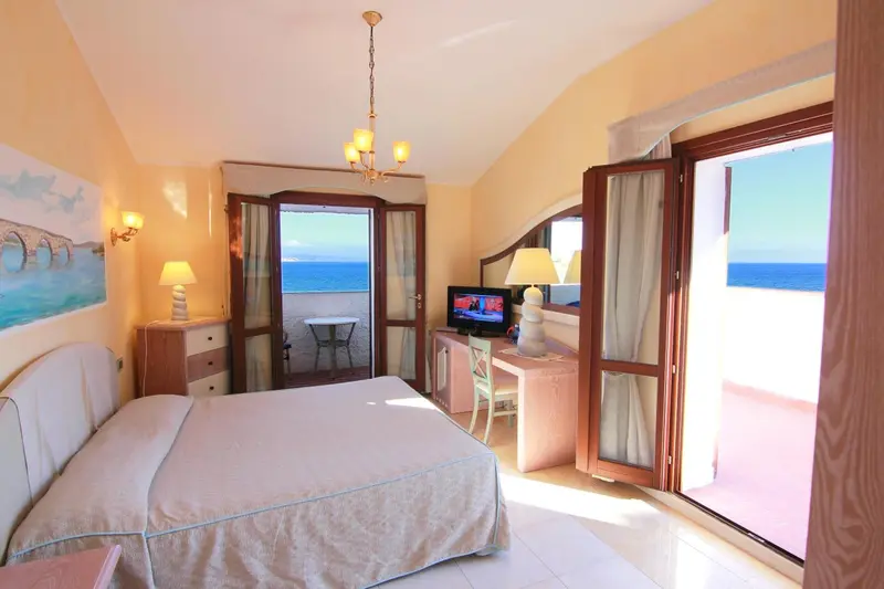 Chambre lumineuse avec un lit double et une vue sur la mer.