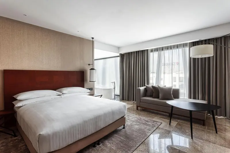 Une chambre lumineuse avec un grand lit et un coin salon près d'une fenêtre.