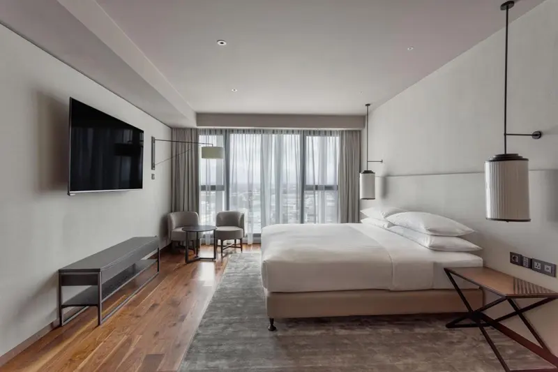 Une chambre moderne avec un grand lit et un espace salon près d'une fenêtre.