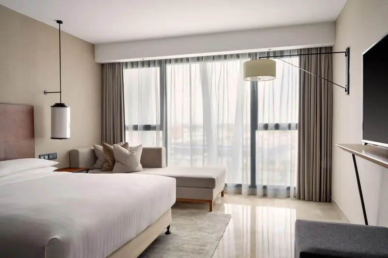 Une chambre lumineuse avec un grand lit et un espace détente près d'une fenêtre.