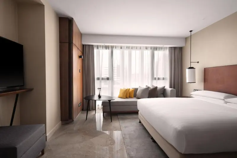 Une chambre lumineuse avec un grand lit et un coin salon près d'une fenêtre.