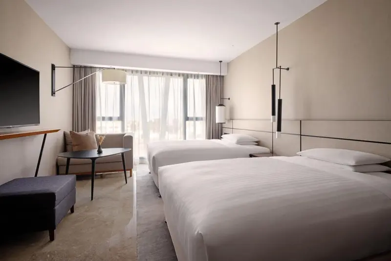 Chambre lumineuse avec deux lits simples et un coin salon.
