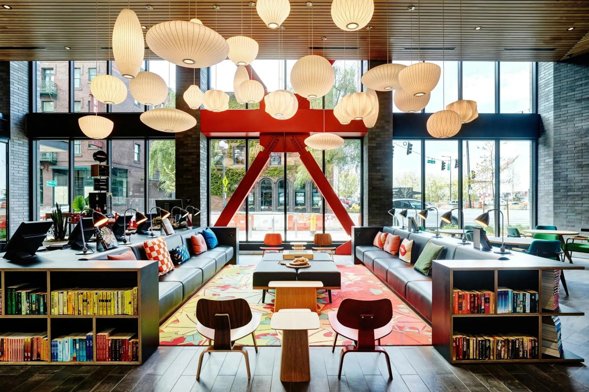Un espace de détente intérieur lumineux avec des canapés colorés et des luminaires suspendus.