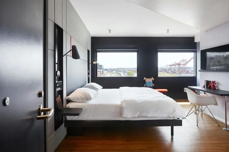Une chambre moderne avec un lit blanc et un bureau près d'une fenêtre.