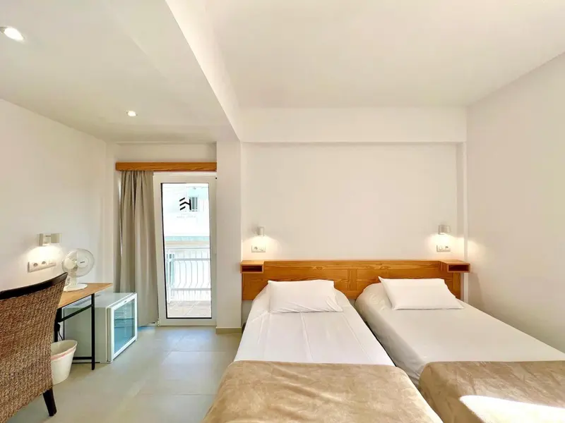 Chambre lumineuse avec deux lits simples et une porte-fenêtre donnant sur une terrasse.