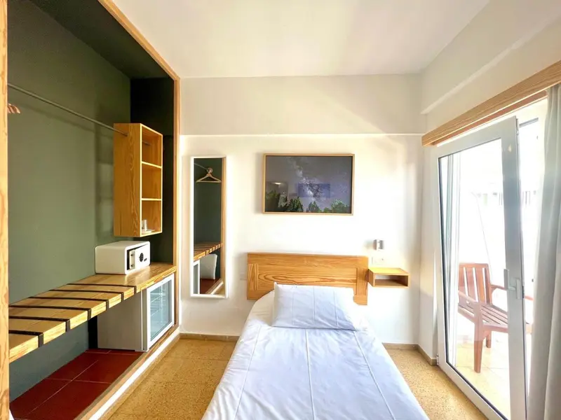 Une chambre lumineuse avec un lit simple et un accès à une terrasse.