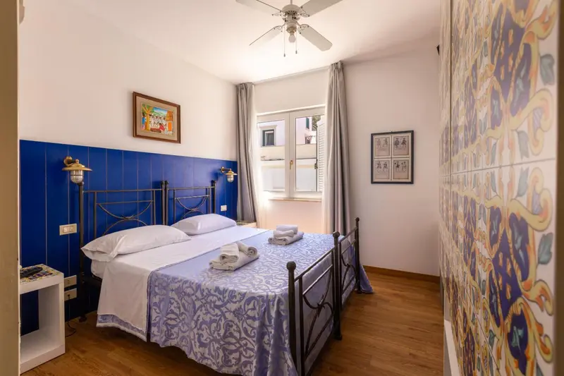 Chambre lumineuse avec un lit double et des murs décorés de carreaux.