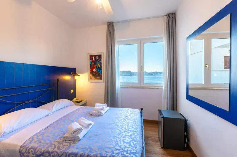 Chambre lumineuse avec un lit double et vue sur la mer.