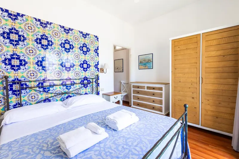 Une chambre lumineuse avec un lit recouvert d'une courtepointe bleue et un mur décoré de carreaux colorés.