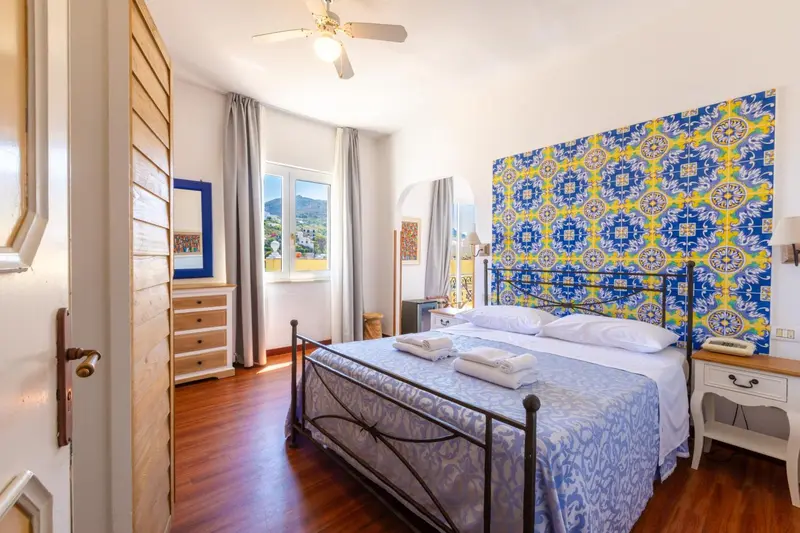 Une chambre lumineuse avec un lit double et un mur décoré de carreaux colorés.