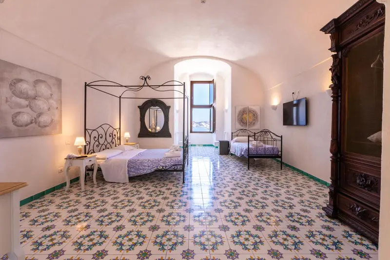 Une chambre lumineuse avec un lit à baldaquin et un sol carrelé décoratif.