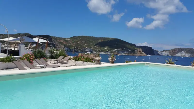 Transats alignés au bord d'une piscine à débordement avec vue sur la mer.