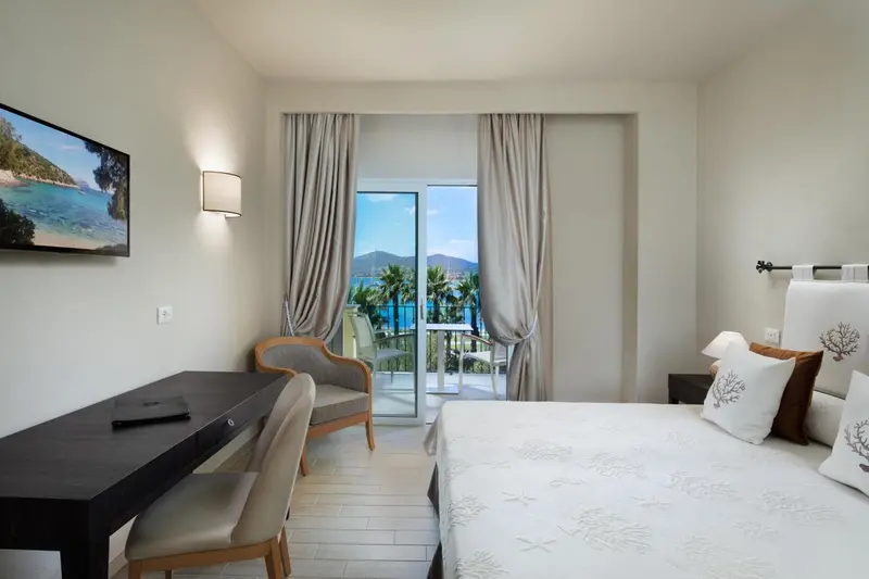 Chambre lumineuse avec vue sur la mer depuis un balcon.