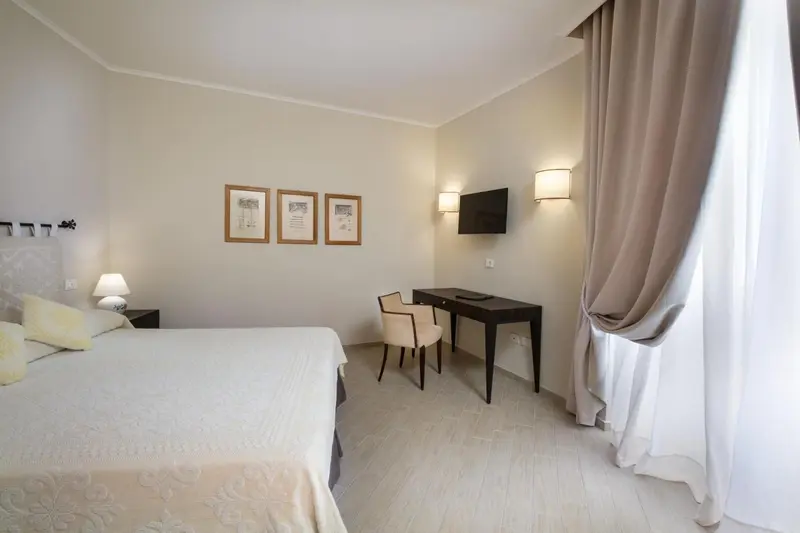 Une chambre lumineuse avec un lit, un bureau et des rideaux.