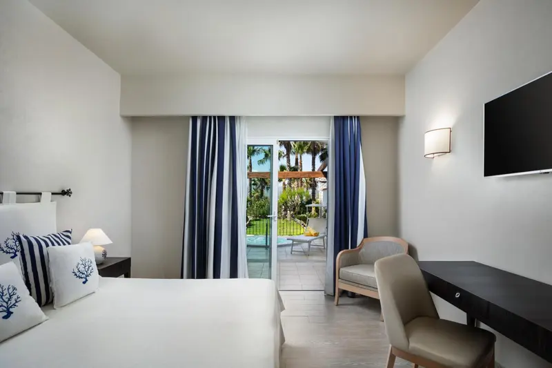 Une chambre lumineuse avec un lit double et un accès à une terrasse.