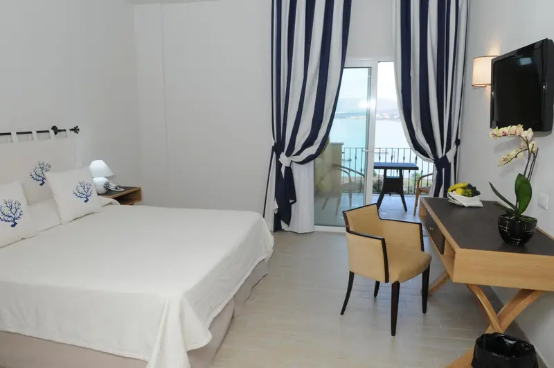 Chambre lumineuse avec un lit recouvert de blanc et une vue sur la mer.