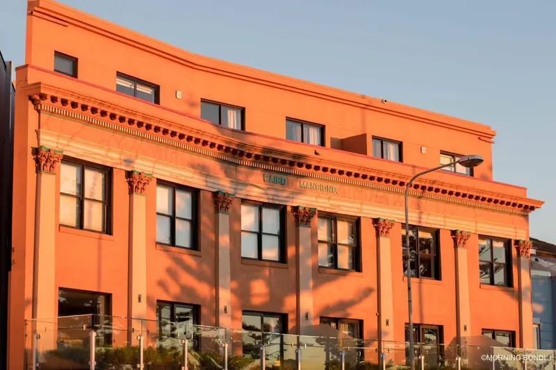 Facade d'un bâtiment orange éclairée par le soleil couchant.