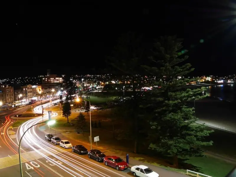 Vue nocturne sur une ville illuminée avec des traces de circulation lumineuses.
