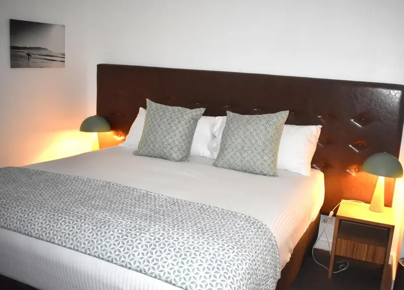 Une chambre lumineuse avec un grand lit recouvert d'une couette à motifs.