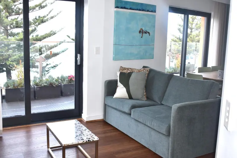 Un canapé vert clair et une table basse dans un intérieur lumineux avec vue sur une terrasse.