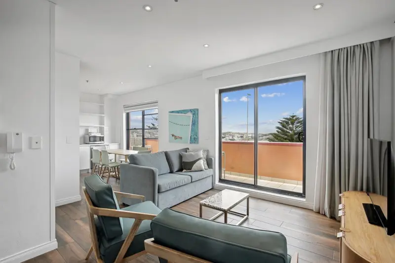 Espace de vie lumineux avec canapé, fauteuils et vue sur la mer.