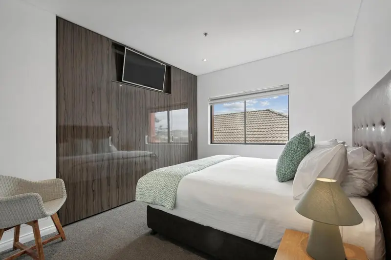 Une chambre moderne avec un grand lit et une télévision murale.