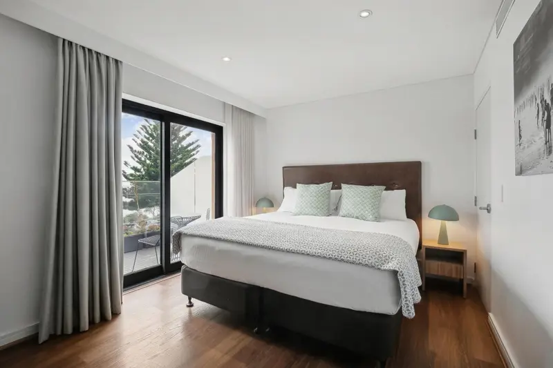 Une chambre lumineuse avec un grand lit et un accès à une terrasse.